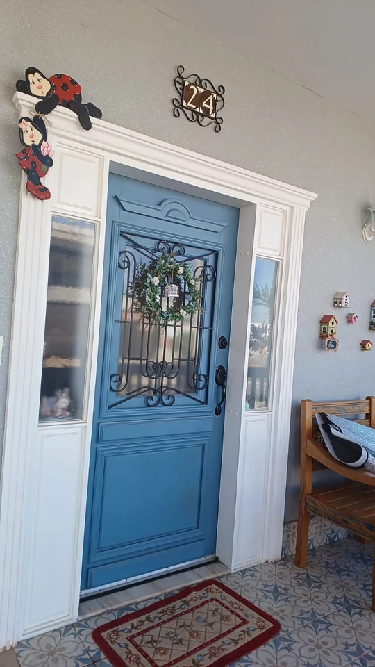 Porta azul com vidro decorado, moldura branca e maçaneta metálica.