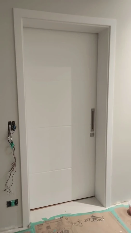 Porta branca com puxador embutido em ambiente com acabamento em andamento.