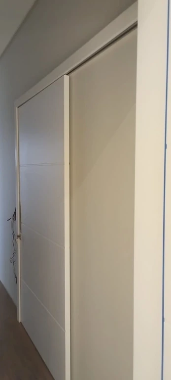 Porta branca de correr vista de lado em um corredor.