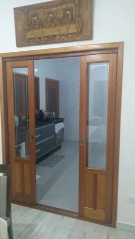 Porta de madeira com vidro parcialmente aberta para um ambiente interno.