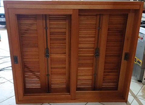 Janela de madeira com venezianas fechadas e ferragens aparentes.