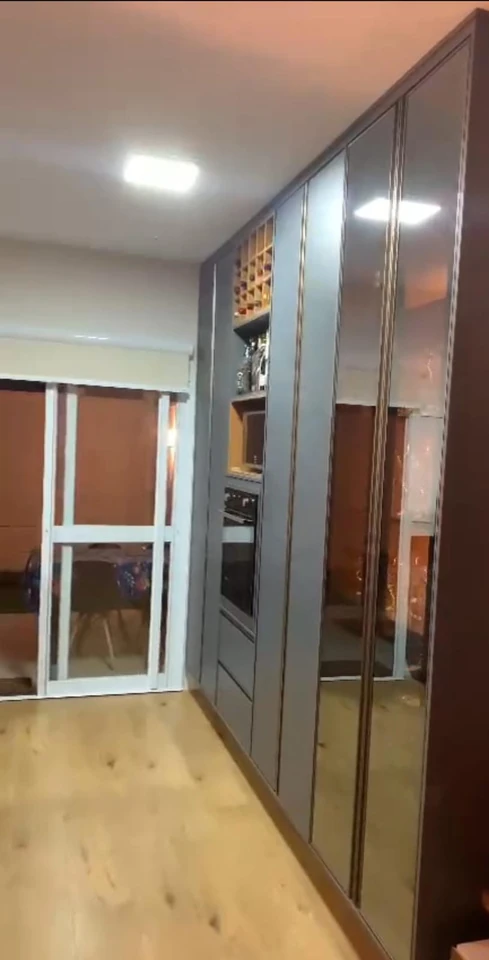 Armário alto cinza com portas espelhadas, nichos e forno embutido.