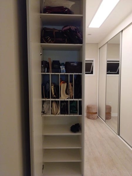 Interior de armário claro com bolsas organizadas em prateleiras e nichos verticais.